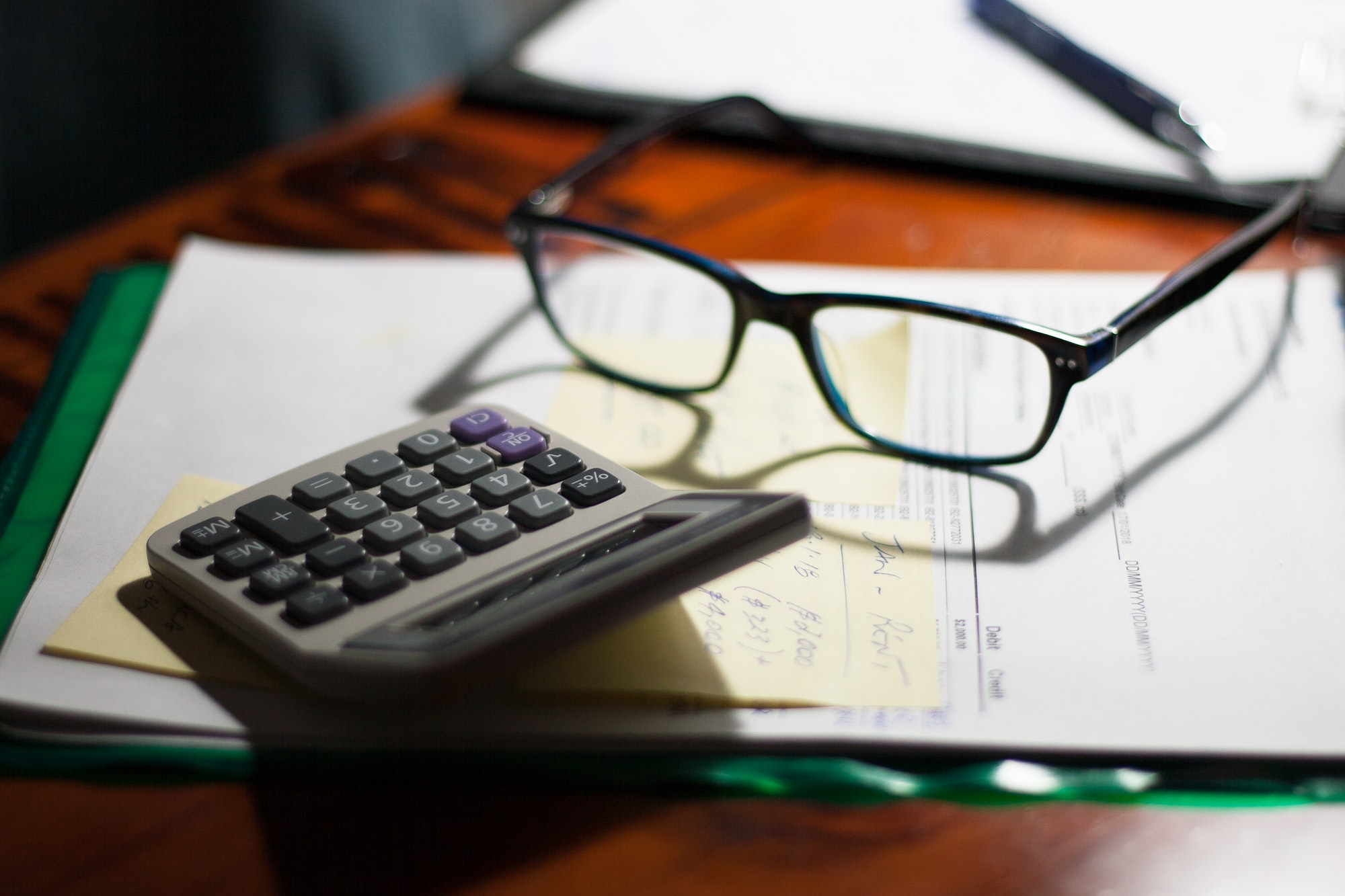 Glasses and calculator on a folder with documents, bills and notes on a desk